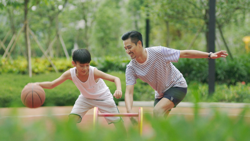 A boy and father playing basketball outside 